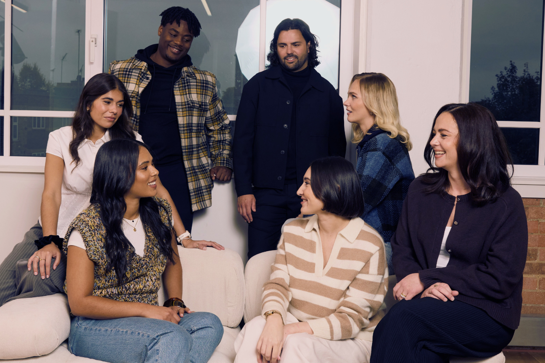 Shaded the studio team sitting on a couch in a modern indoor setting

